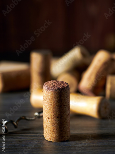 A closeup of a cork from a bottle of wine stands on a wooden table