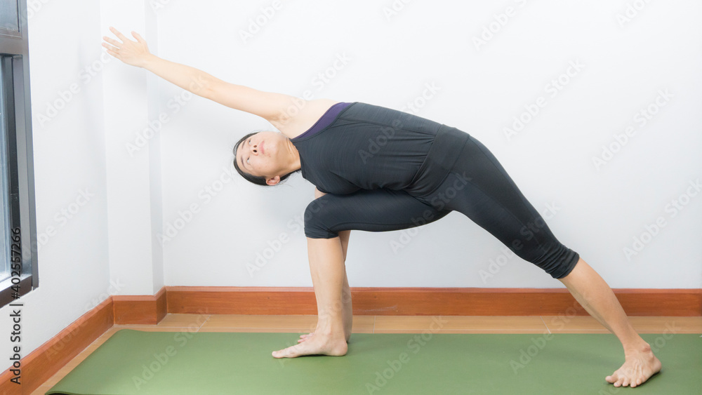 Asian young woman wear a black yoga outfit . Practicing yoga Standing Asanas Action UTTHITA PARSVAKONASANA (extended Side angke pose).Home yoga practice on white background