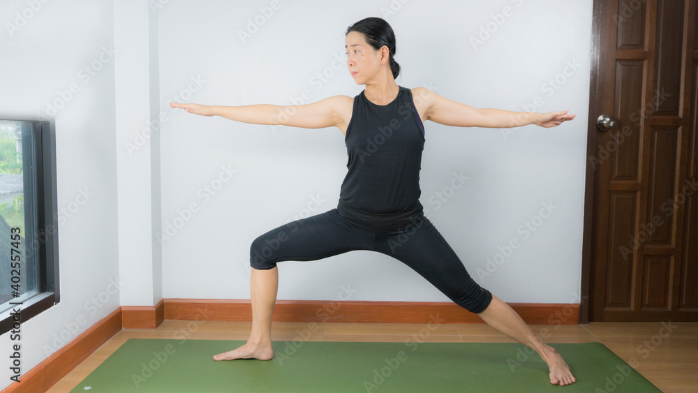 Asian young woman wear a black yoga outfit . Practicing yoga Standing Asanas Action A&B VIRABHADRASANA A&B (warrior I,II). Home yoga practice on white background Asian young woman wear a black yoga outfit . Practicing yoga Standing Asanas Action A&B VIRABHADRASANA A&B (warrior I,II). Home yoga practice on white background