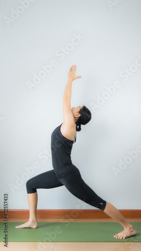 Asian young woman wear a black yoga outfit . Practicing yoga Standing Asanas Action A&B VIRABHADRASANA A&B (warrior I,II). Home yoga practice on white background