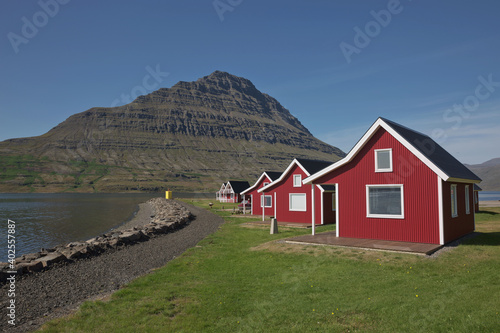 Traditional red painted wooden panel house with mighty Holmatindur mountain in the background in Eskifjordur, East Iceland