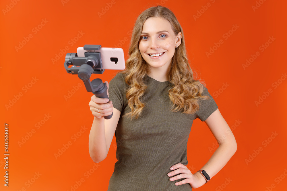 Portrait of attractive young girl taking selfie on smartphone isolated on orange background Portrait of attractive young girl taking selfie on smartphone isolated on orange background