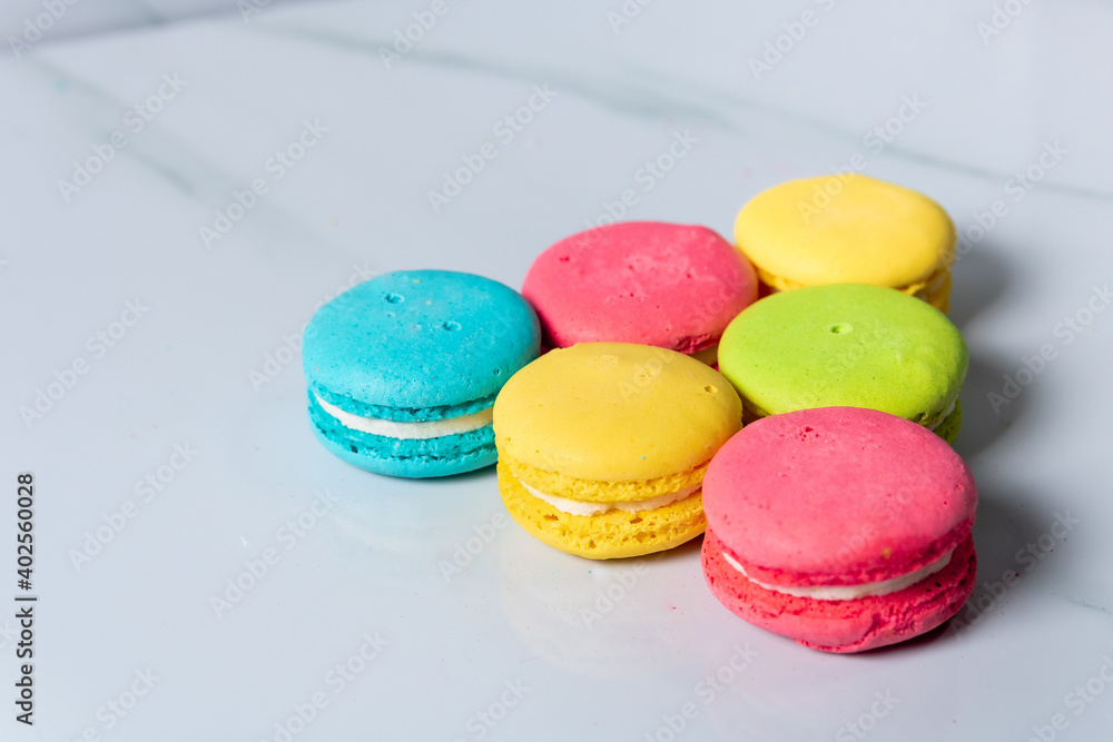 multicolored macaroon cookies lie on a white kitchen table multicolored macaroon cookies lie on a white kitchen table