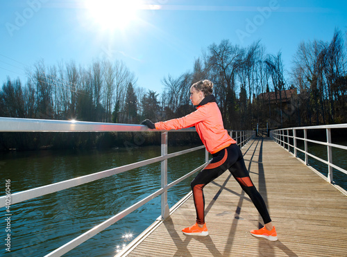 Young athlete woman exercises and stretches on the walkway of a bridge