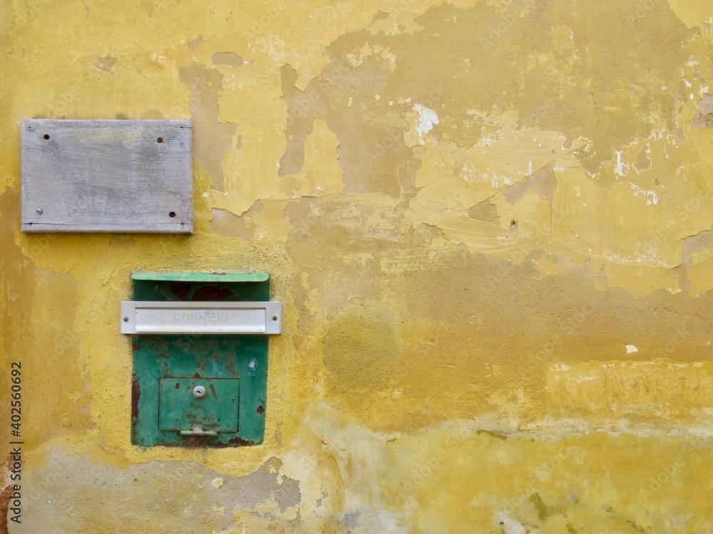 old yellow wall with green postbox