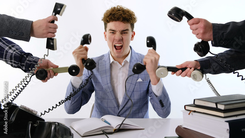 фотографія A lot of phone calls: Busy Angry assistant agent helper  working and answering a lot of calls at the same time, landline rotary phone