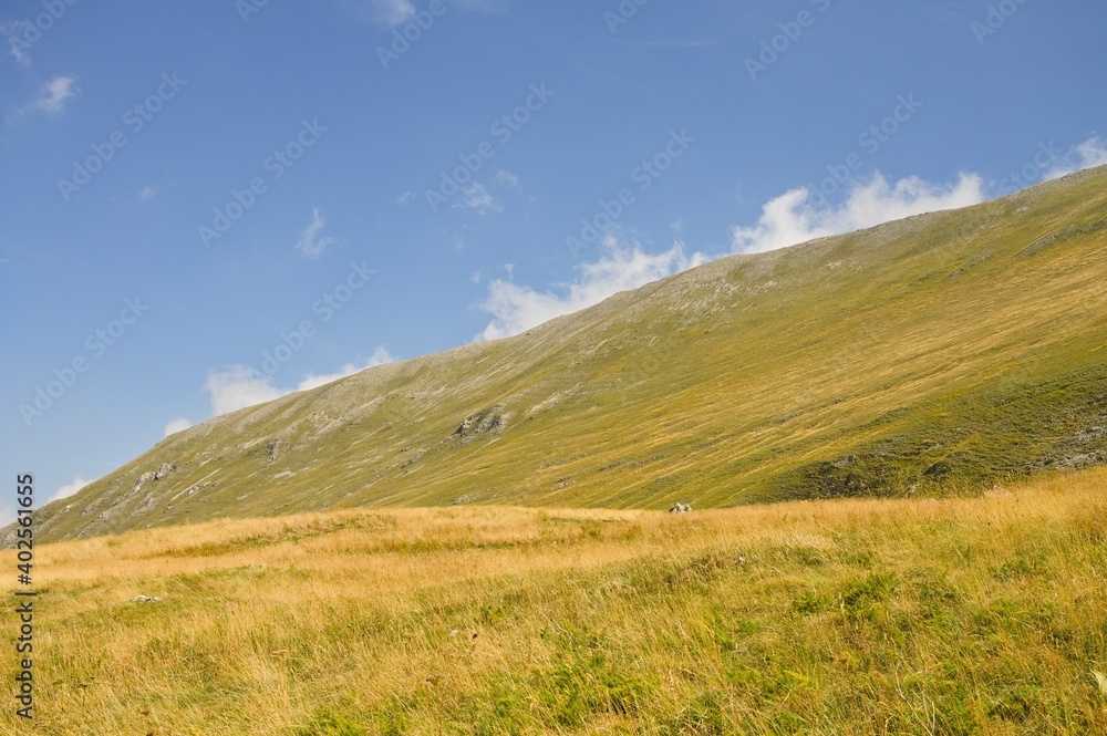 A hillside meadow on a sunny day with some clouds in the sky (Sibillini, Marche, Italy)