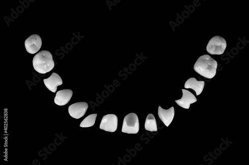 composition of ceramic dental veneers in the form of a smile on a black background, photo in black and white style