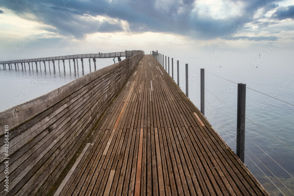 Stunning foggy view of the pedestrian wooden bridge (Holzsteg) crossing the Zurich Lake at its narrowest point between Hurden (Seedam) and Rapperswil, Switzerland