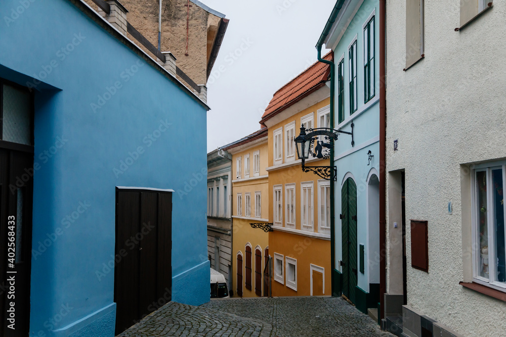 Narrow picturesque colorful street with yellow and blue baroque and renaissance historical buildings in the city center of Roudnice and Labem, Central Bohemia, Czech Republic