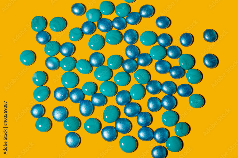 Blue and turquoise glass pebbles on a yellow background. Blue and turquoise glass pebbles on a yellow background.