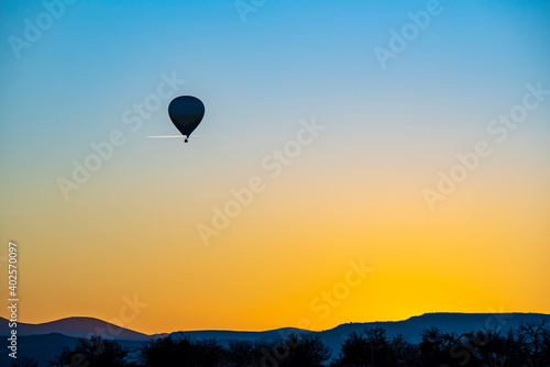 Hot air balloon flying near a aircraft over Cappadocia, orange sky © attraction art