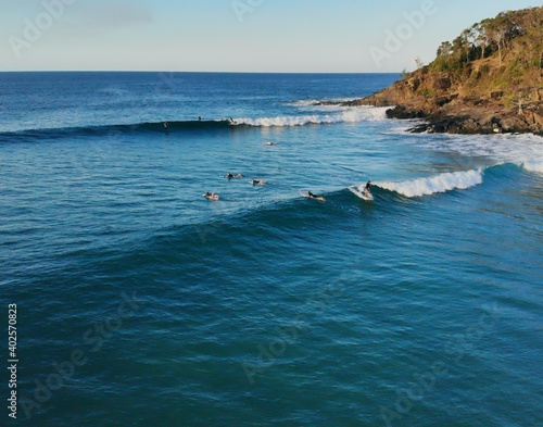 Perfect waves break in Tea Tree Bay, Noosa Heads as the sun set casts shadows on Noosa National Park