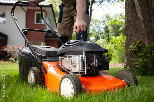 Obraz na plátně Closeup of professional gardener turning on the lawn mower
