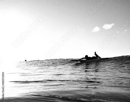Surf minimalism - Overexposed surfer paddles for a wave