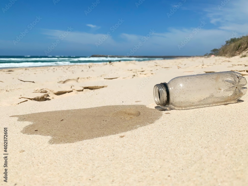 Obraz premium Single use plastic bottle collected from the ocean spills out onto the sand - human waste, ocean pollution
