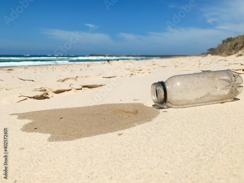 Single use plastic bottle collected from the ocean spills out onto the sand - human waste, ocean pollution