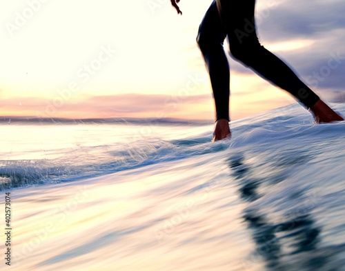 Slow shutter - Longboarder cross stepping up a surfboard at sunset