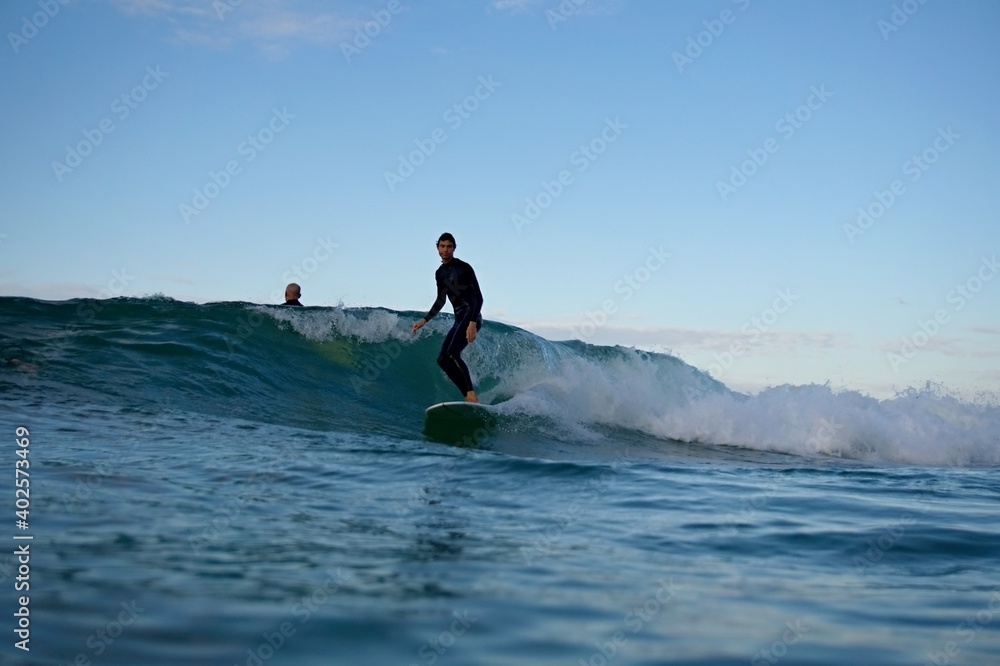 A surfer cruises along a sunset wave at Snapper Rocks