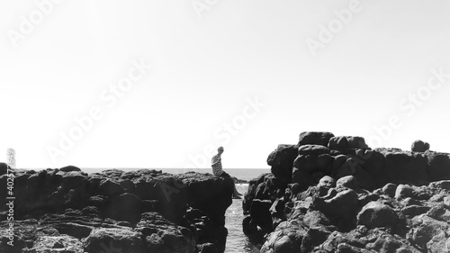 Black and white - sitting on the edge of a small cliffe above the ocean photo