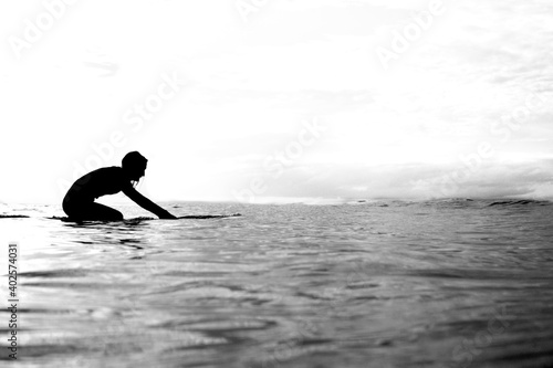 Minimalism - Surfer on his knees paddling across the horizon