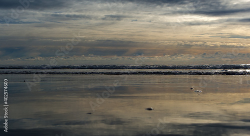 Winter morning on the beach with small waves and dark sand