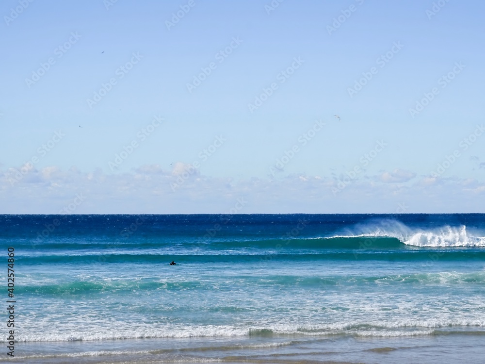 A lone surfer paddles out on a board as a perfect wave goes unridden infront of him