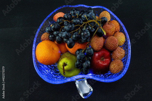 Still life in a crystal plate with blue illumination on a black background with a top view