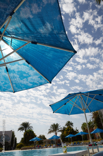 blue umbrella from the sun palm trees and the sky in the clouds