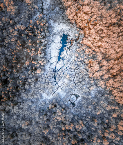 Sunrise over a snowy valley with river flowing through the forest in Sigulda. Aerial view with dark storm clouds.