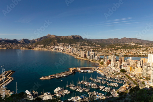 Coastline of the Mediterranean resort of Calpe, Spain with sea and yachts, lake, skyscrapers and mountain range.