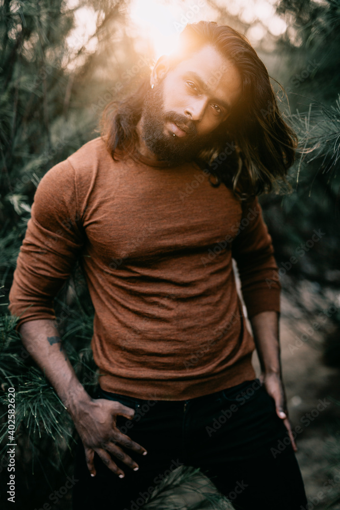Fototapeta premium Long hair bearded young man posing in outdoor with tree background.
