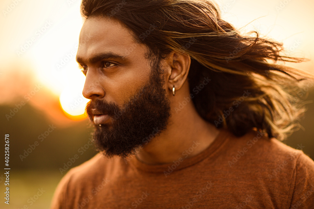 Long hair bearded young man portrait enjoying breezy wind in nature background. Long hair bearded young man portrait enjoying breezy wind in nature background.