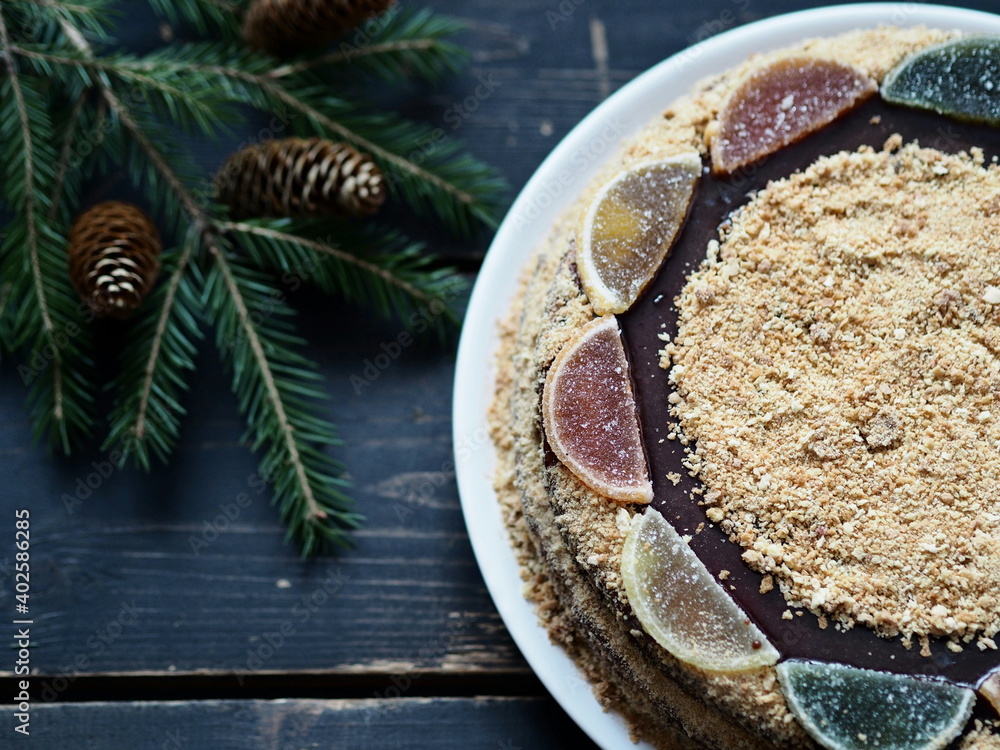 Rustic food background.Round homemade honey layered cake on dark background with fir branches and place for text. Rustic food background.Round homemade honey layered cake on dark background with fir branches and place for text.