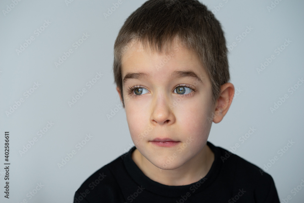 portrait of little boy with big blue eyes, looking thoughtfully to the side, light background, black shirt portrait of little boy with big blue eyes, looking thoughtfully to the side, light background, black shirt