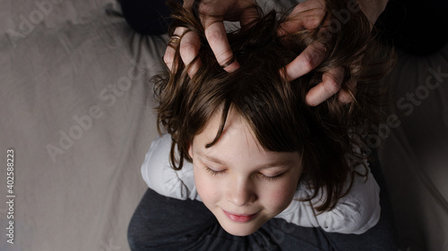 mom gives head massage to daughter at home top view photo