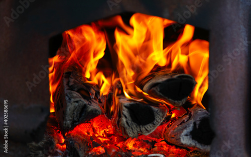 Bright and colorful fire in the oven. Firewood is burning and charcoal is burning. Cozy atmosphere of the evening.