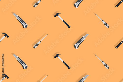 Tools seamless pattern. Tools: hammer, screwdriver and knife on an orange background.