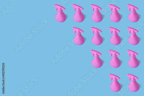 Pattern made of pink bottle spray with cosmetic  hygiene  cleaning liquid on bright blue background