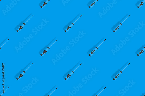 Screwdrivers seamless pattern. Metal screwdrivers with a rubberized handle on a blue background.