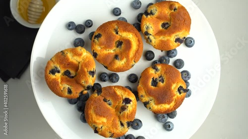 Fresh blueberry muffins spin on a plate. Muffins on a white plate with blueberries and honey close-up on a white background.the view from the top.