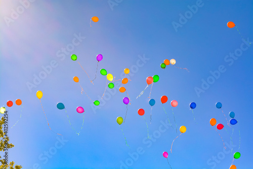 colorful holiday balloons fly away into the blue sky