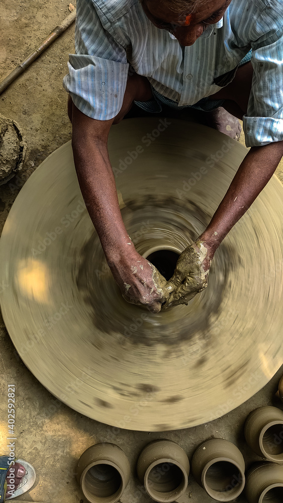 Indian potter crafting pots by hands on sniping potters wheel.