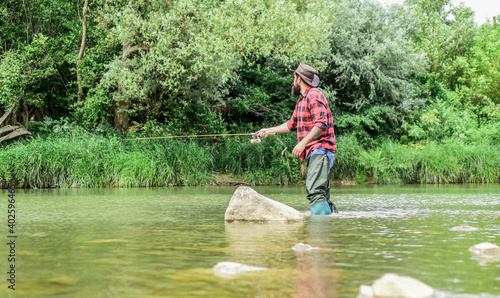 The Addiction is Real. sport activity hobby. experienced fisher in water. Successful fly fishing. summer weekend. man catching fish. mature man fly fishing. fisherman show fishing technique use rod