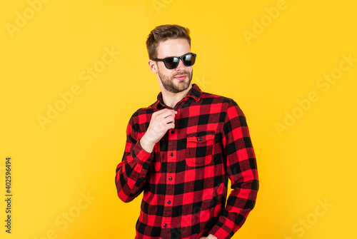 young handsome man in checkered shirt and sunglasses has bristle on face, summer
