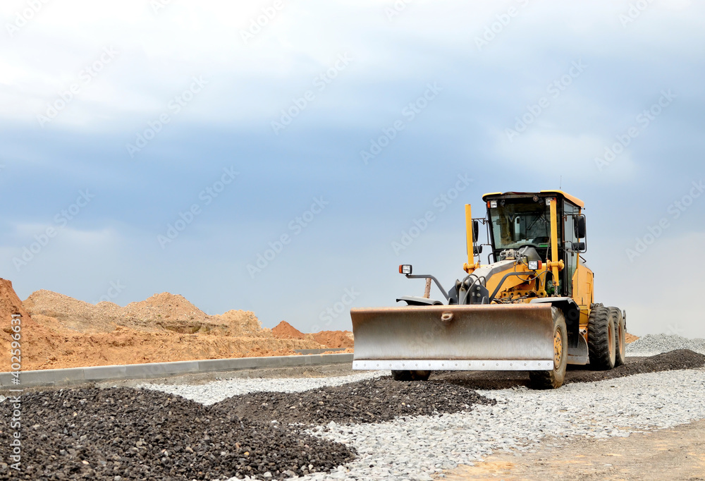 Сonstruction machine Motor Grader at a construction site level the ground and gravel stones for the construction of a new asphalt road. Road construction equipment