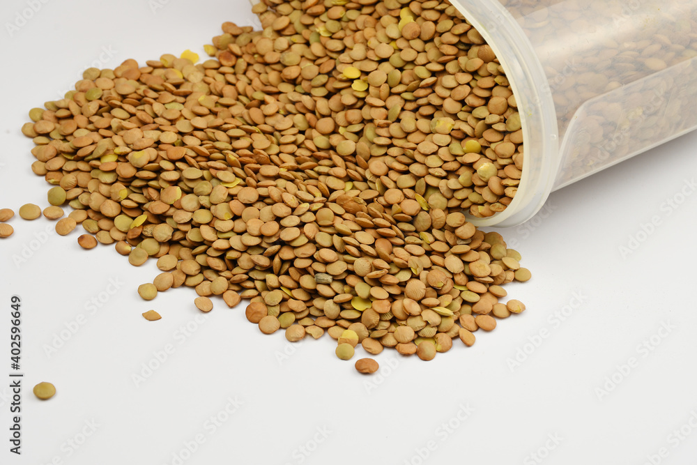 Plastic jar full of green lentils, close-up view on white background. Plastic jar full of green lentils, close-up view on white background.