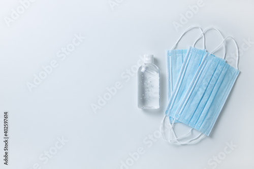 Medical protective  blue face masks  sanitizer gel  on white background  close-up  flatly  minimal style  copy space. Hygiene concept  protective equipment  prevention of spread of viral infections