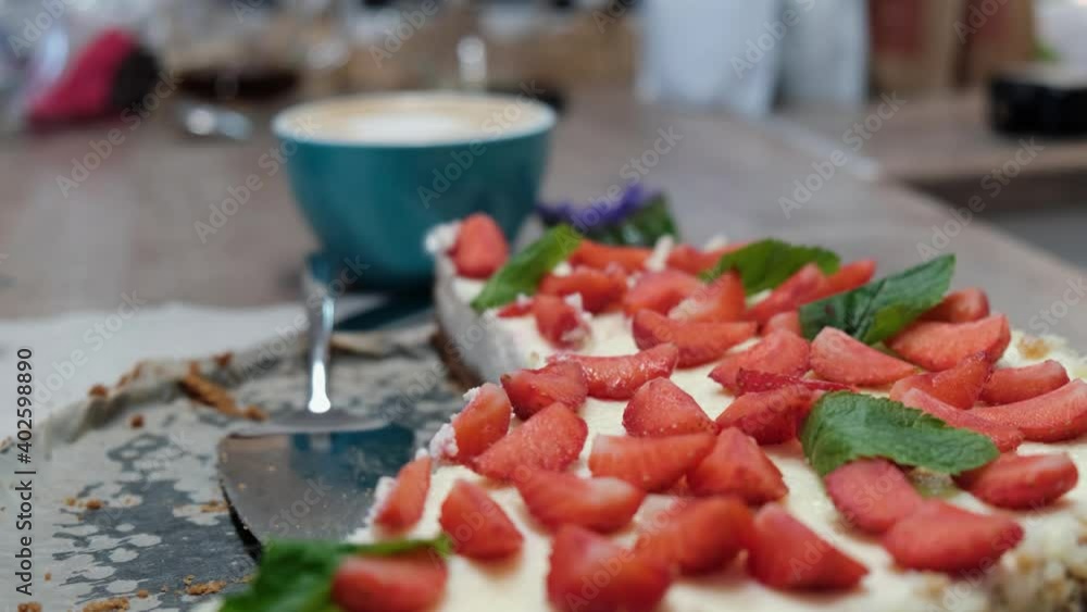 Delicious strawberry homemade cheesecake with mint against the backdrop of a cup of cappuccino, selective focus, 4k Delicious strawberry homemade cheesecake with mint against the backdrop of a cup of cappuccino, selective focus, 4k