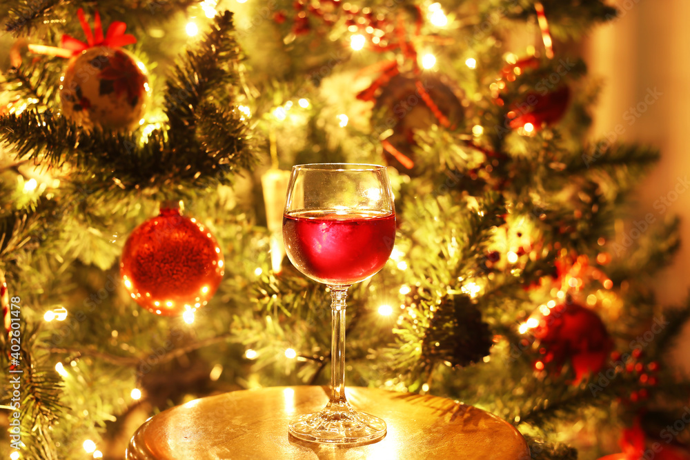 glass with red wine in front of the night Christmas tree glass with red wine in front of the night Christmas tree